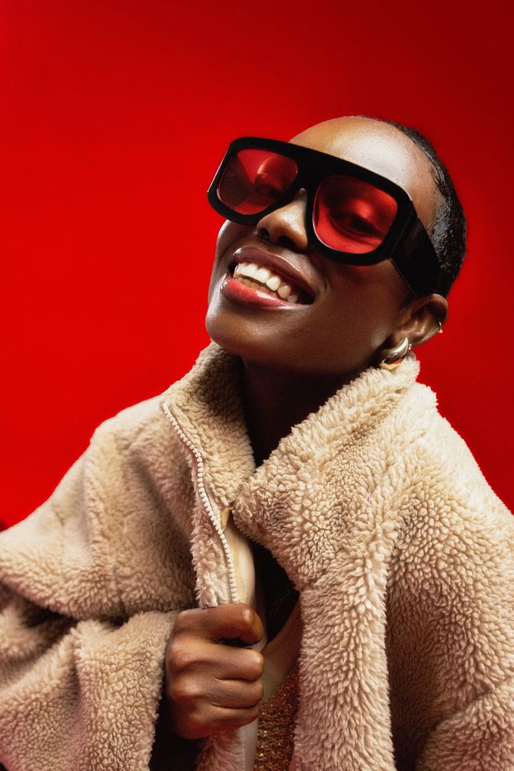 Lifestyle-Portrait mit roter Designer-Sonnenbrille und Teddyjacke vor rotem Hintergrund