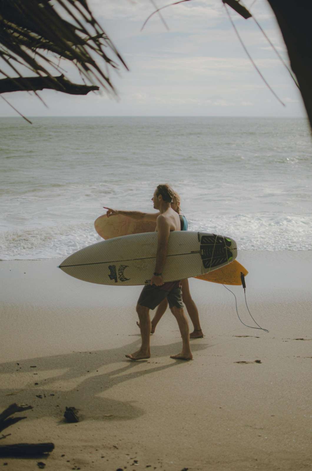 Surfers walk on a beach with surfboards - – surfboard rental in Costa Rica