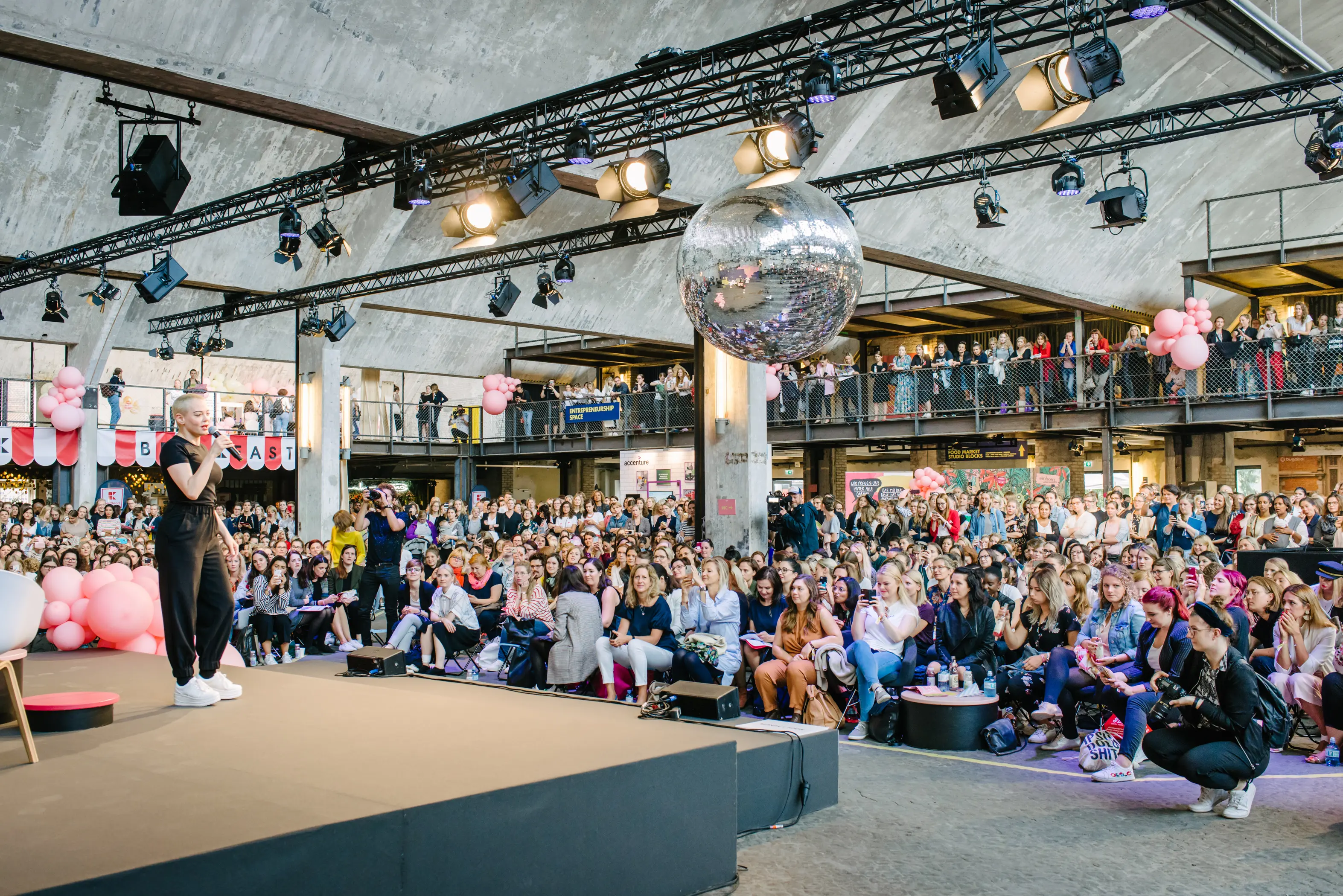 Speaker on stage in front of the packed audience at the FEMALE FUTURE FORCE DAY with disco ball, spotlights on trusses and balloons on the gallery.