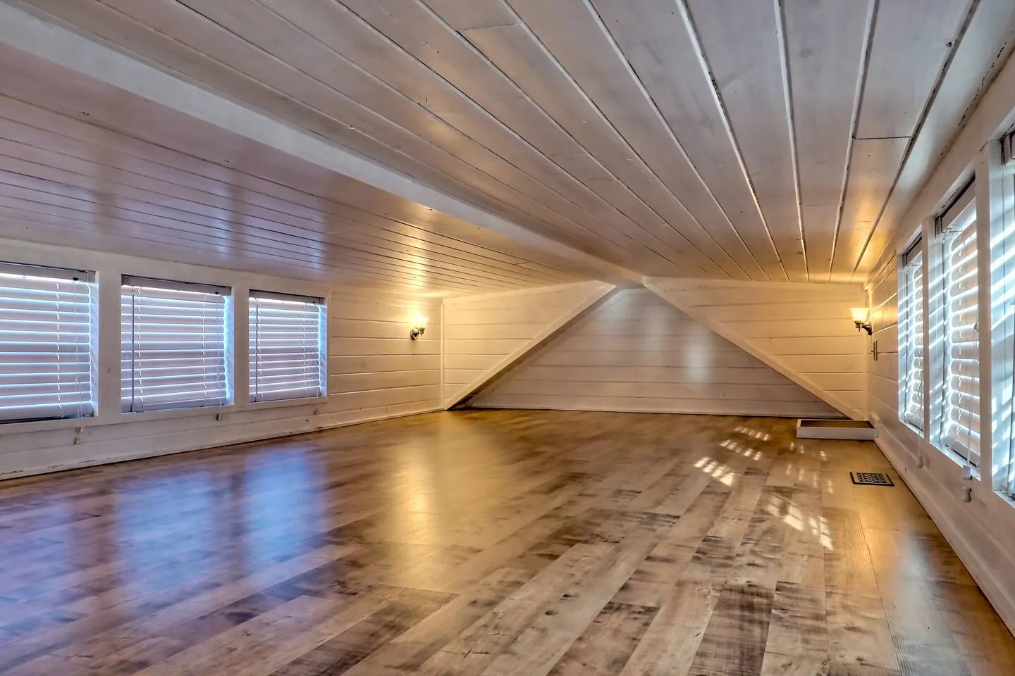 Open loft space in Tiny Tuck with wood floors and a row of windows