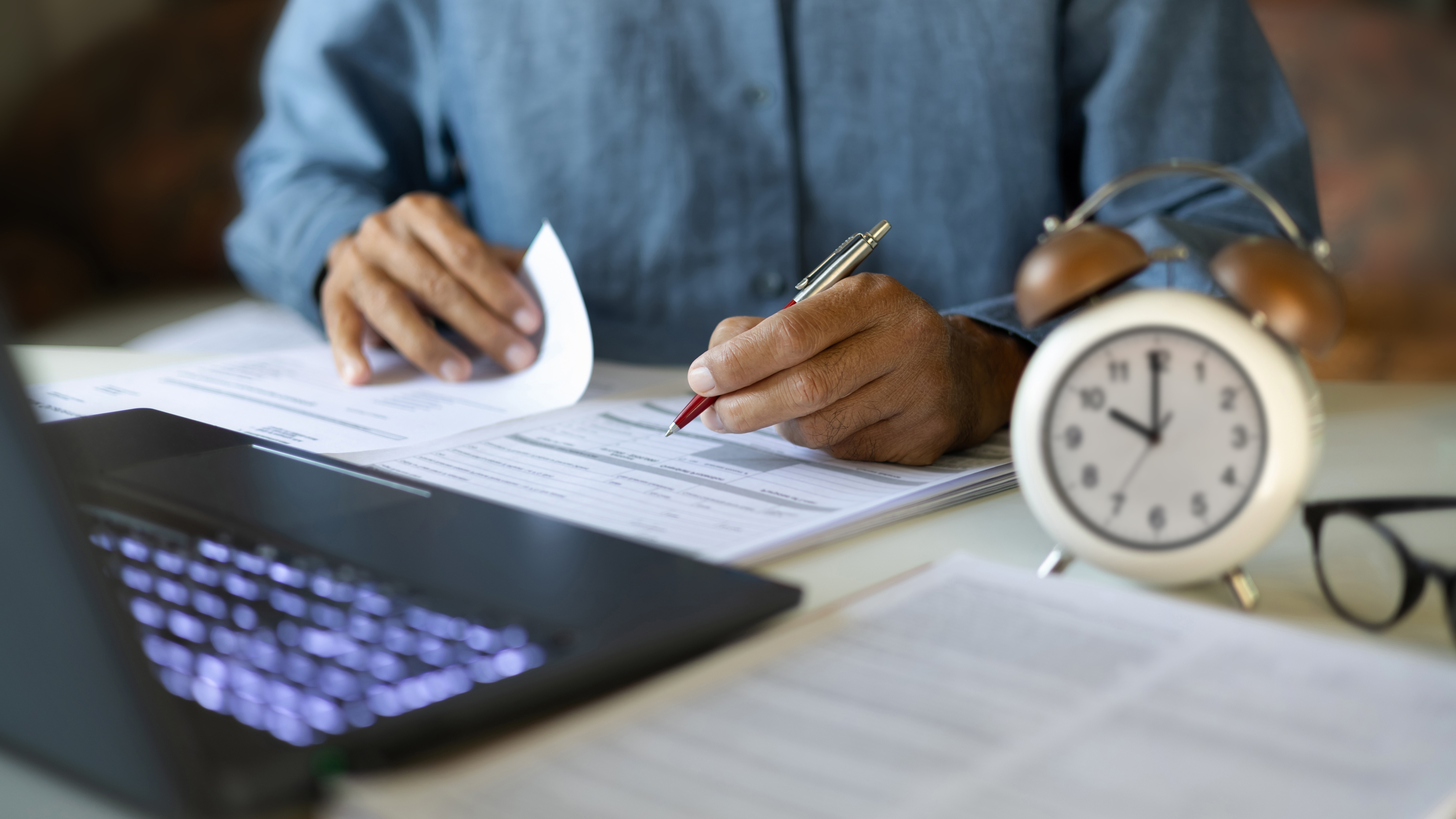 Businessman reviewing loan documents quickly with clock on desk representing fast bridging finance decisions