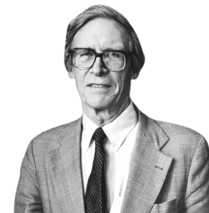 A black-and-white portrait of a man with glasses and a composed expression, wearing a suit jacket, white shirt, and dark tie. His formal attire and thoughtful demeanor suggest he is a distinguished academic or intellectual, likely from the late 20th century.