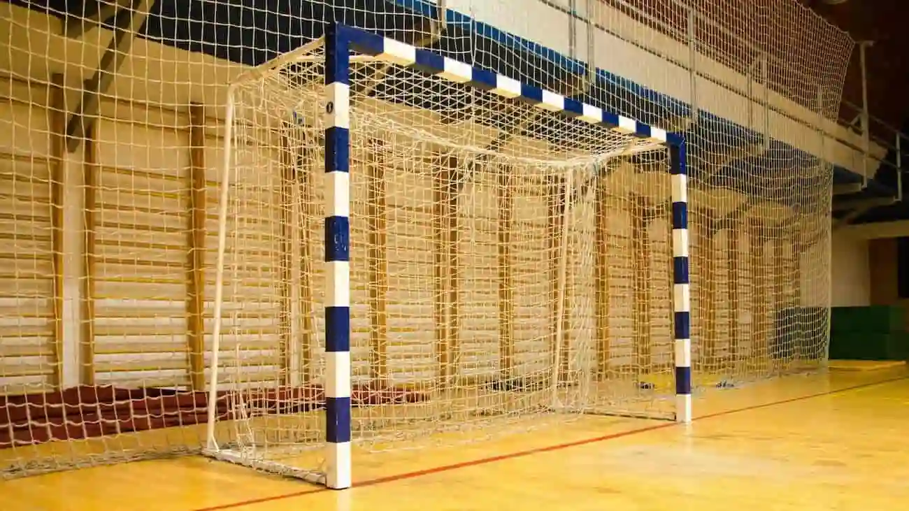 Futsal-Tor in einer Sporthalle mit blau-weißen gestreiften Pfosten und einem gelben Netz, das die Ausrüstung zeigt, die bei Futsal-Turnieren und Hallenturnieren gemäß den BFV-Vorschriften verwendet wird.