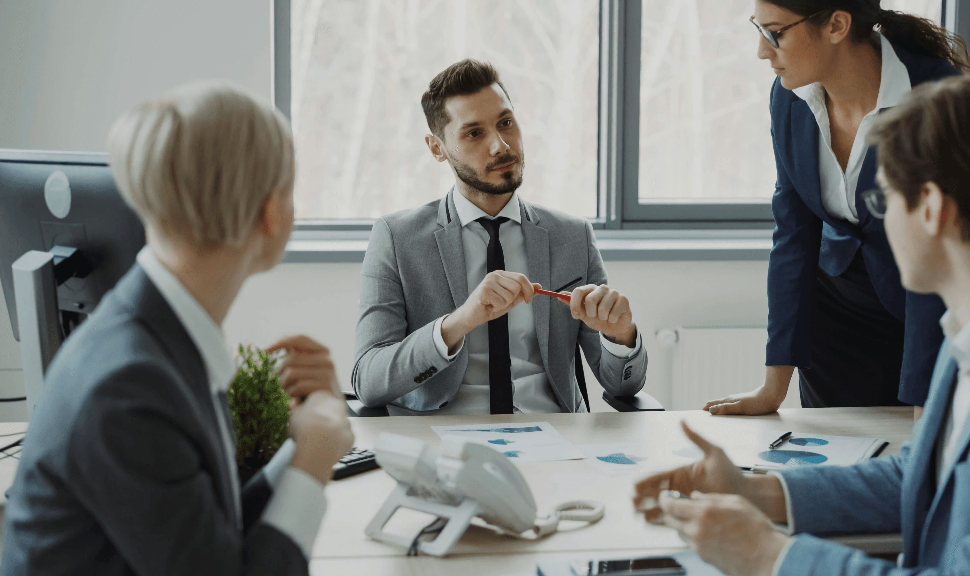 PRO services Abu Dhabi with four businessmen in a strategic meeting, reviewing corporate documents for a seamless procedure.