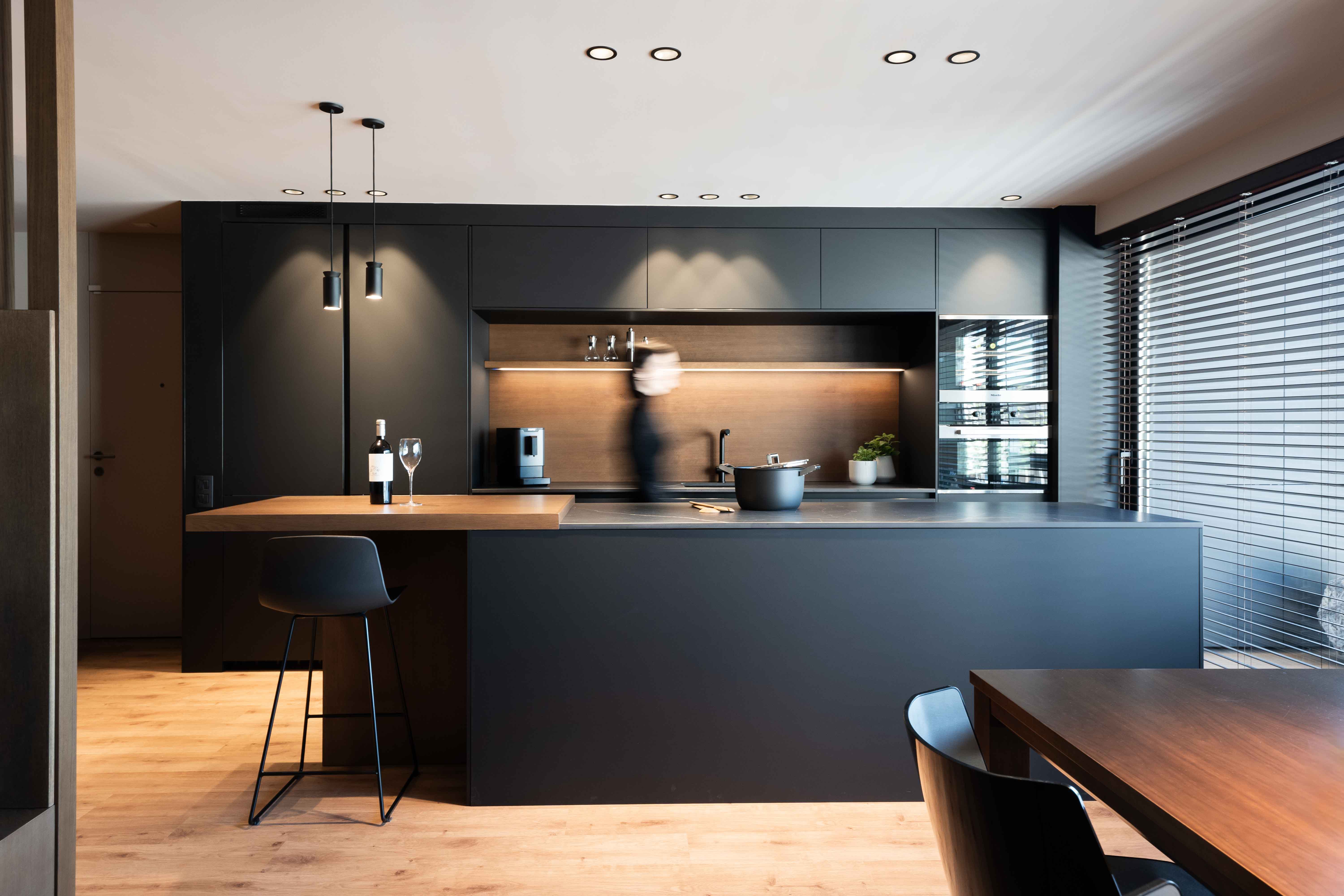 Cocina-comedor abierta de estilo oscuro con muebles y encimera de acabados negros