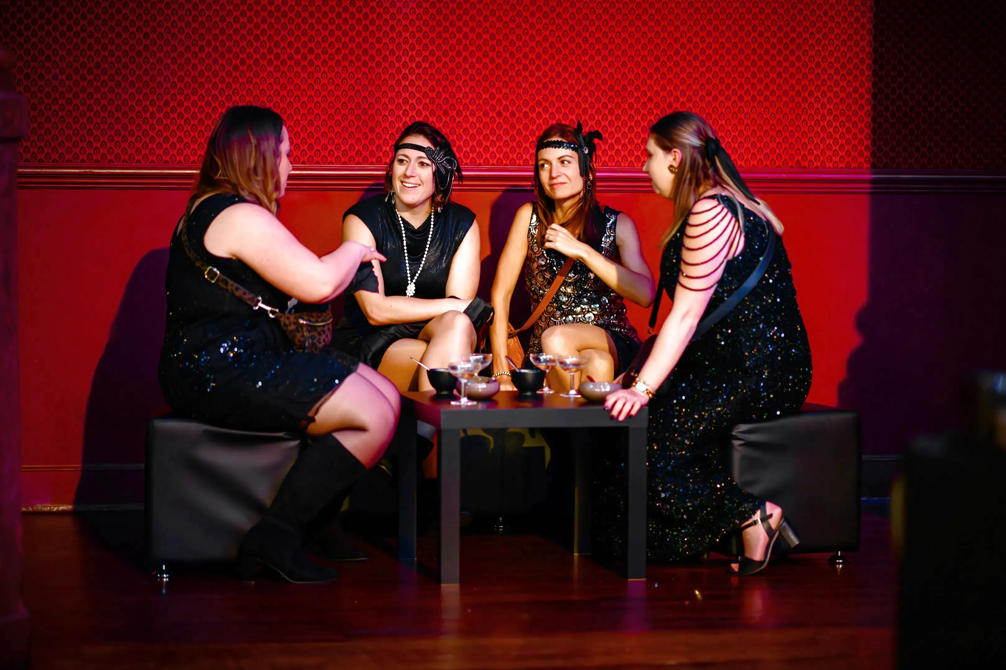 Groupe de participantes en tenue années 30 discutant autour d’une table pendant une soirée événementielle