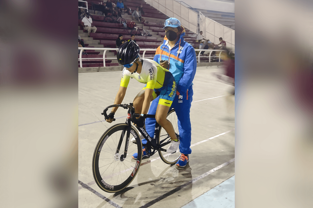 Entrenamiento en velódromo: ciclista en pista con el Coach Marco sujetando la bici, antes de arrancar.