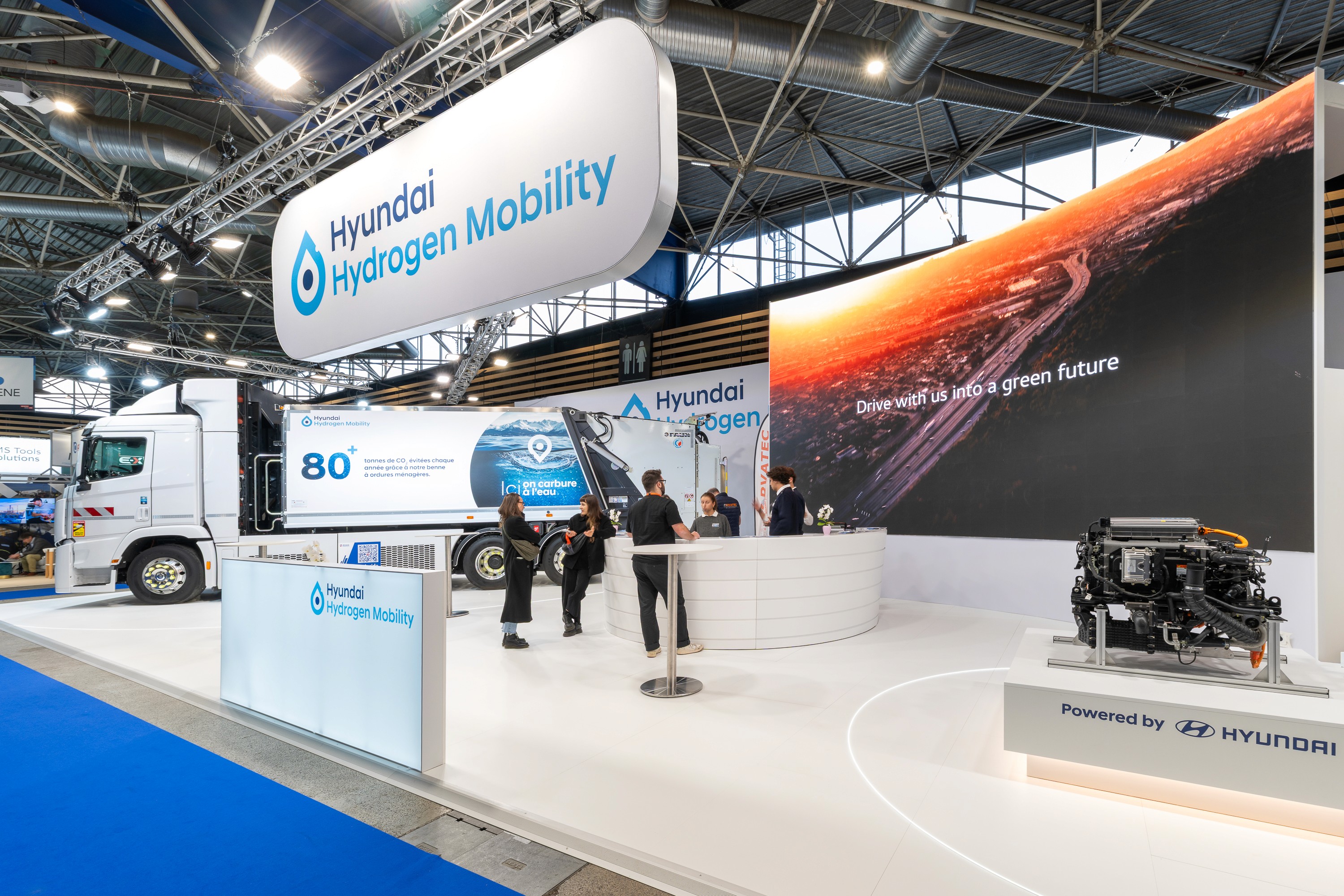 Stand Hyundai Hydrogen Mobility Solutrans Lyon 2026 réalisé par Expace – vue frontale avec grand écran LED incurvé, véhicule hydrogène exposé et structure bleue marine grand format