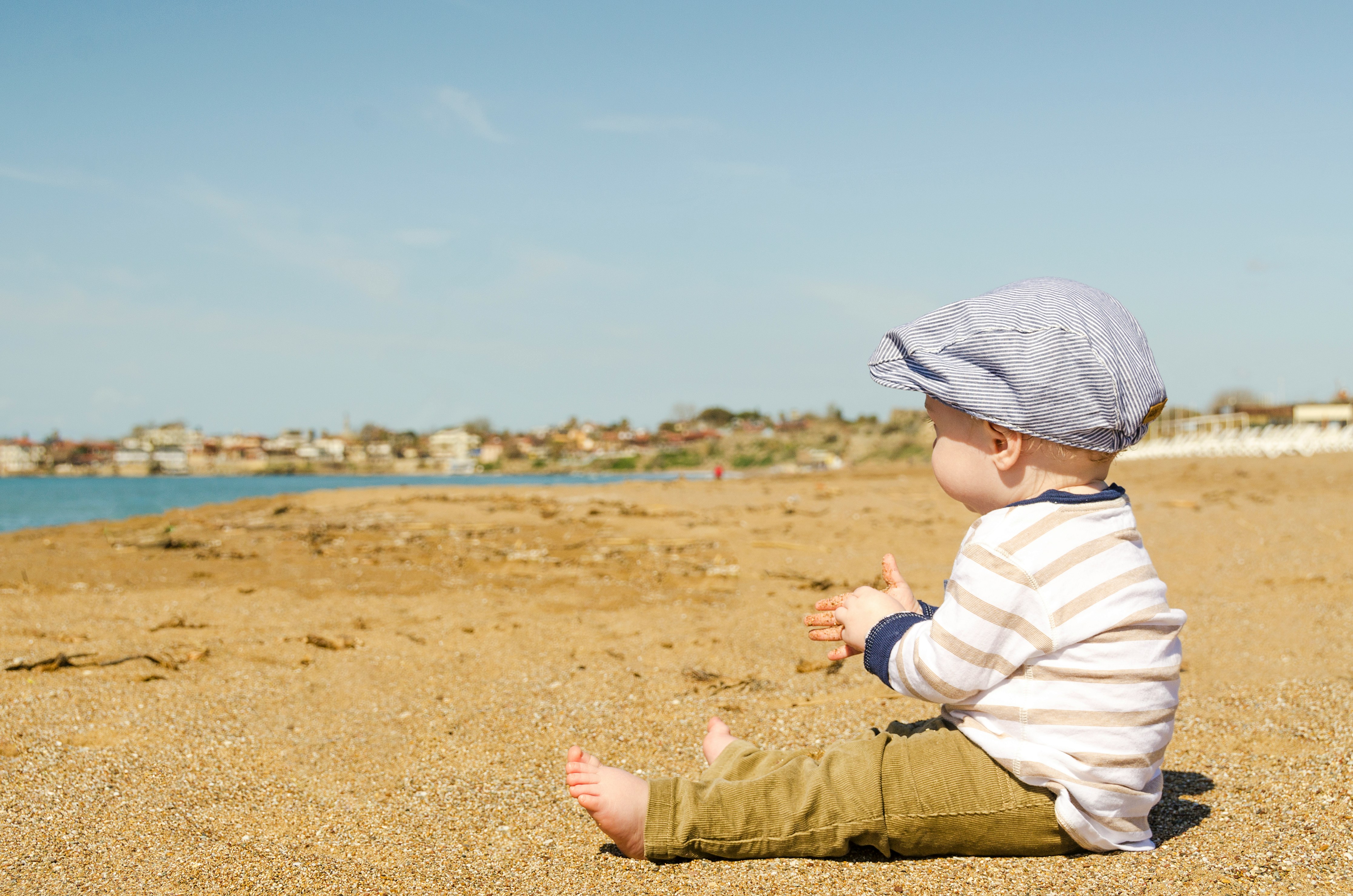 sitting toddler on seashore at daytime