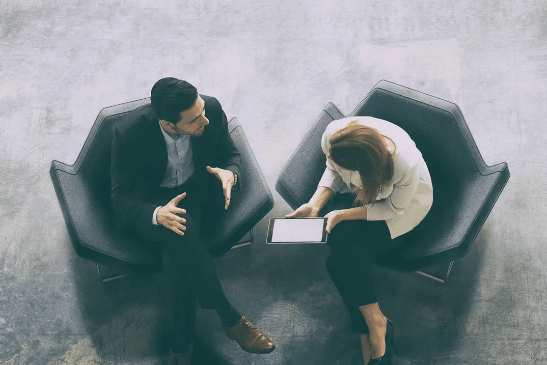 A winding road cuts through rocky terrain, surrounded by patches of green grass and illuminated by sunlight.