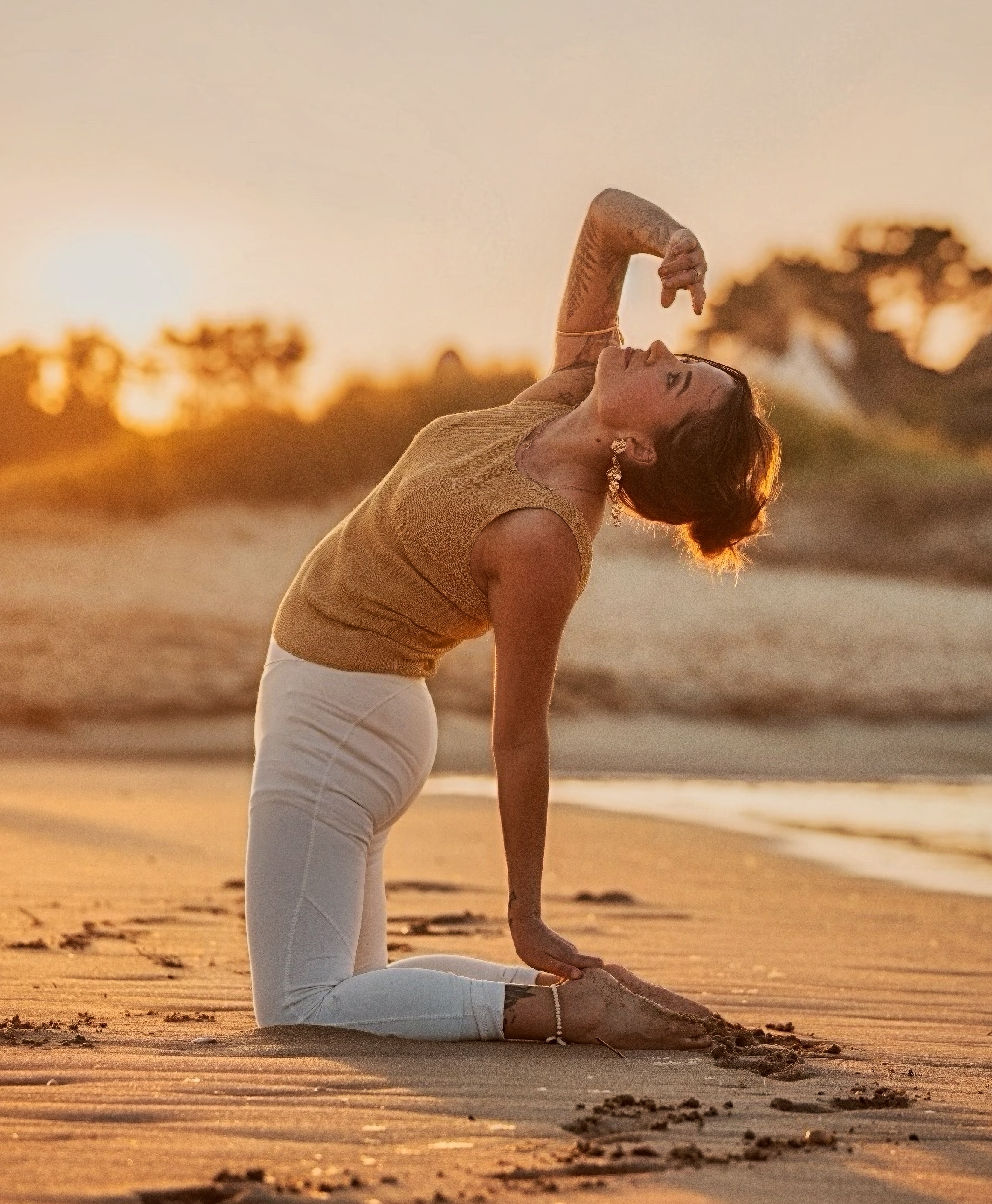 Cours de yoga sur la plage au coucher de soleil, posture de la demi-lune agenouillée
