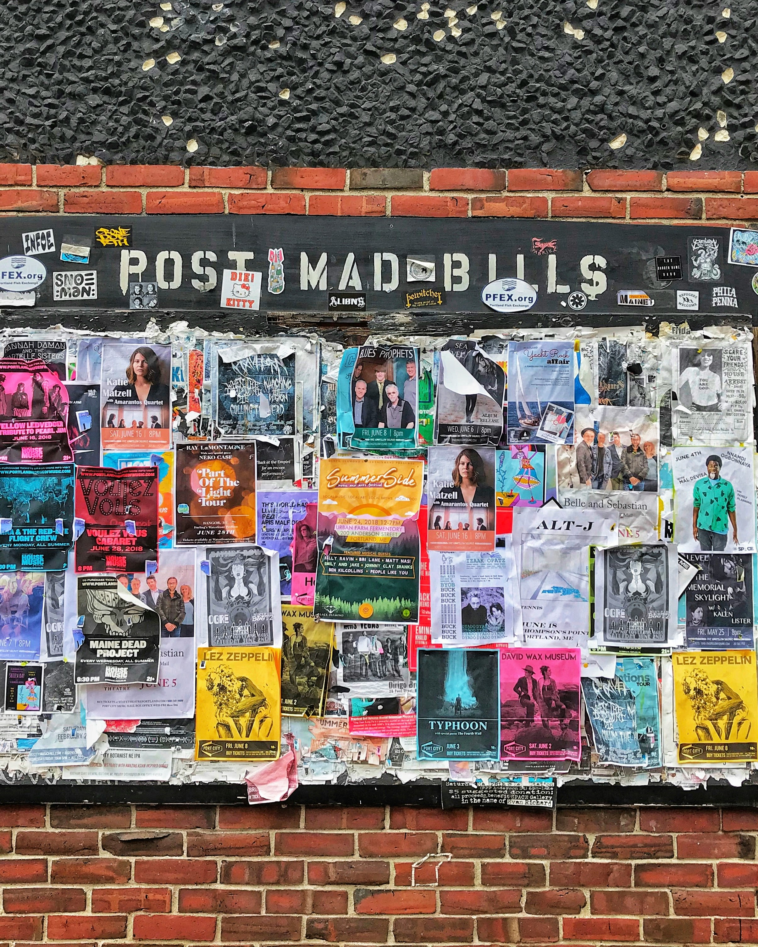 A brick wall covered in colourful posters and flyers, symbolising the shift from traditional advertising to AI-driven placements like future ChatGPT ads, reinforcing the need for AI SEO and AI Visibility optimisation to recover traffic lost to AI.