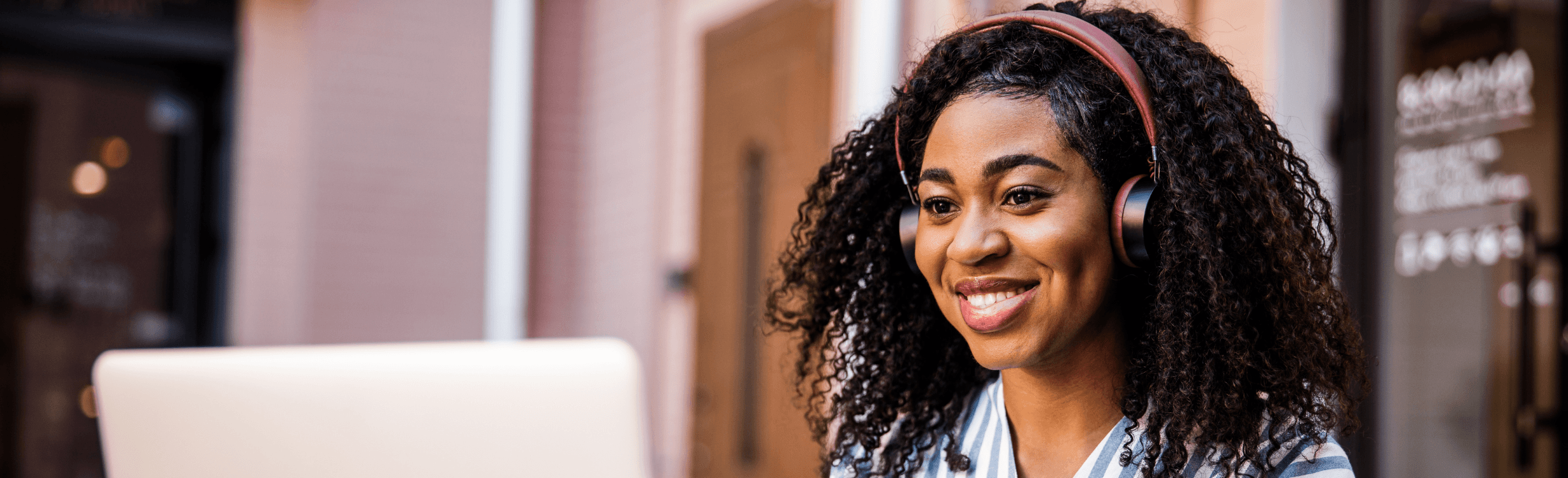 A smiling young woman with curly hair wearing headphones