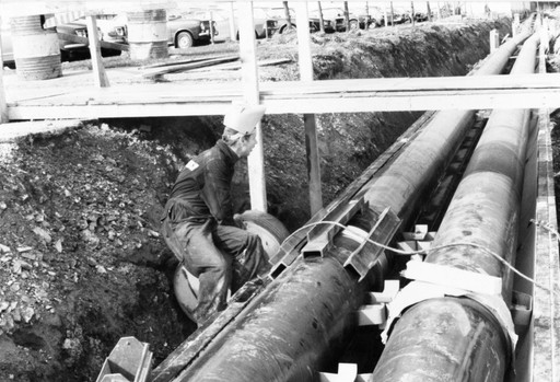 Old photo of person standing on top of district heating pipe