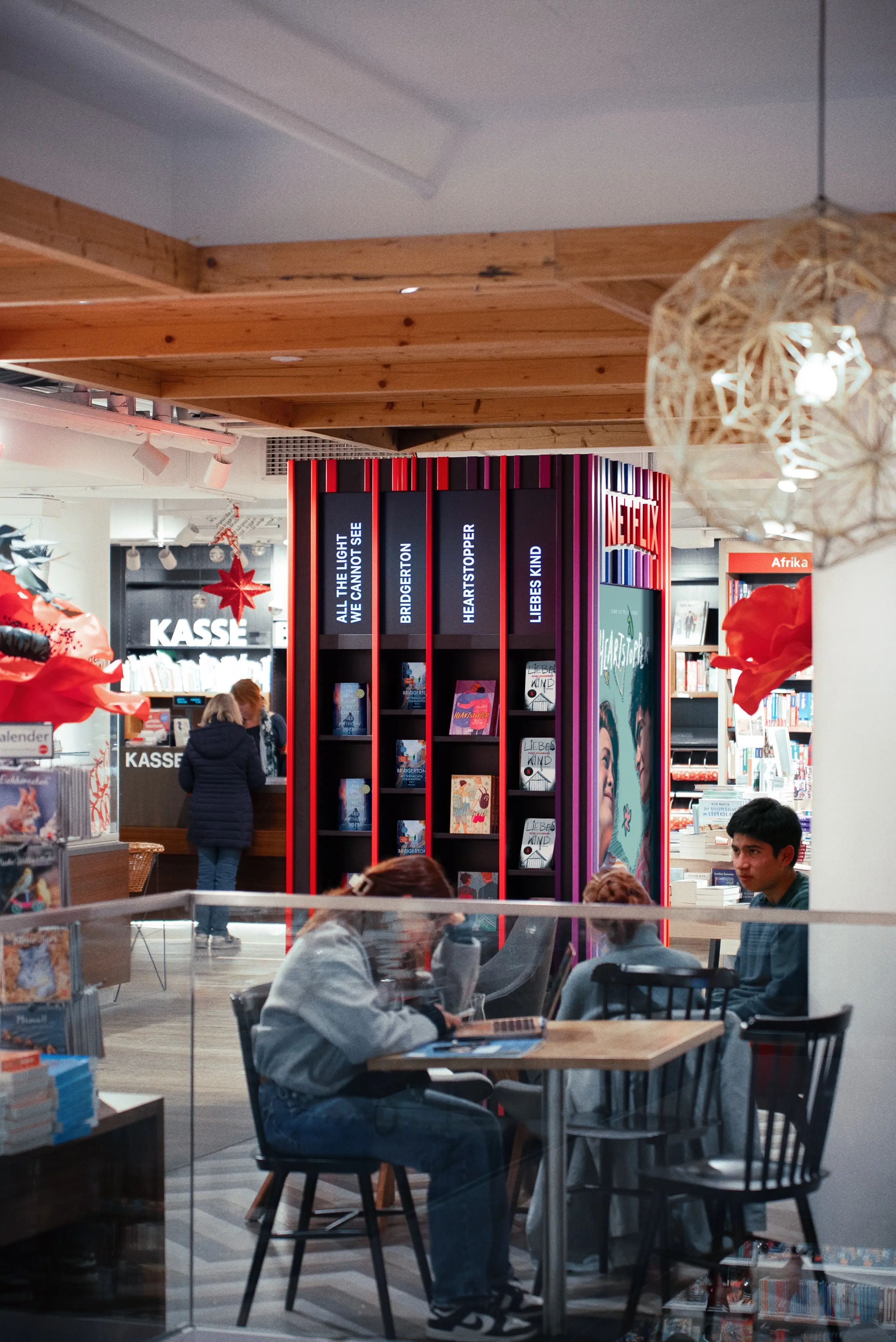 NETFLIX TOWER seen across the bookstore café with guests at tables, showing the striped display with series book titles.