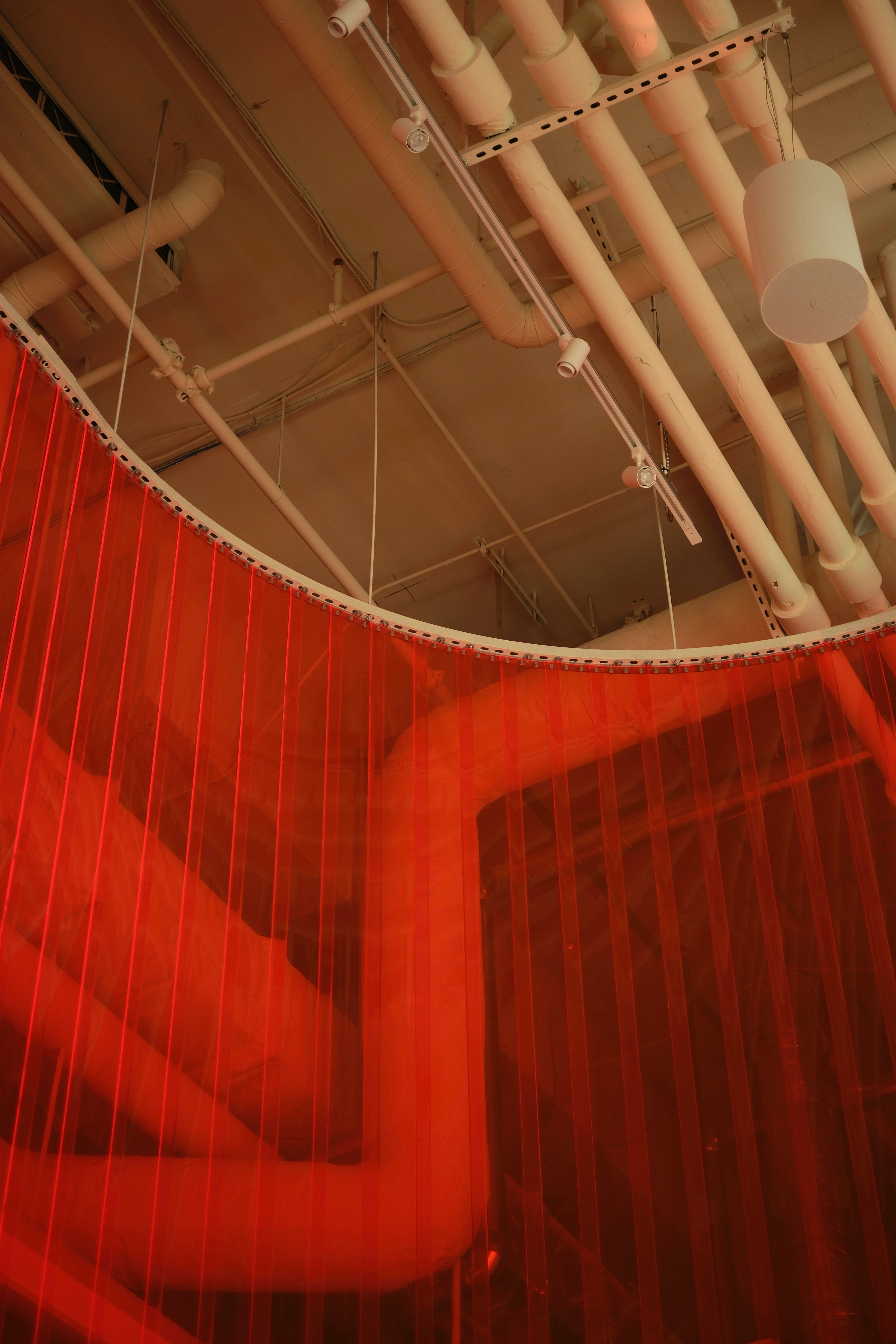 Red netting hangs in front of industrial pipes