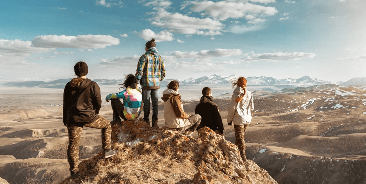 Group of friends standing on a mountain ridge looking out over a vast landscape, illustrating expanded mindsets and enterprise-wide perspective