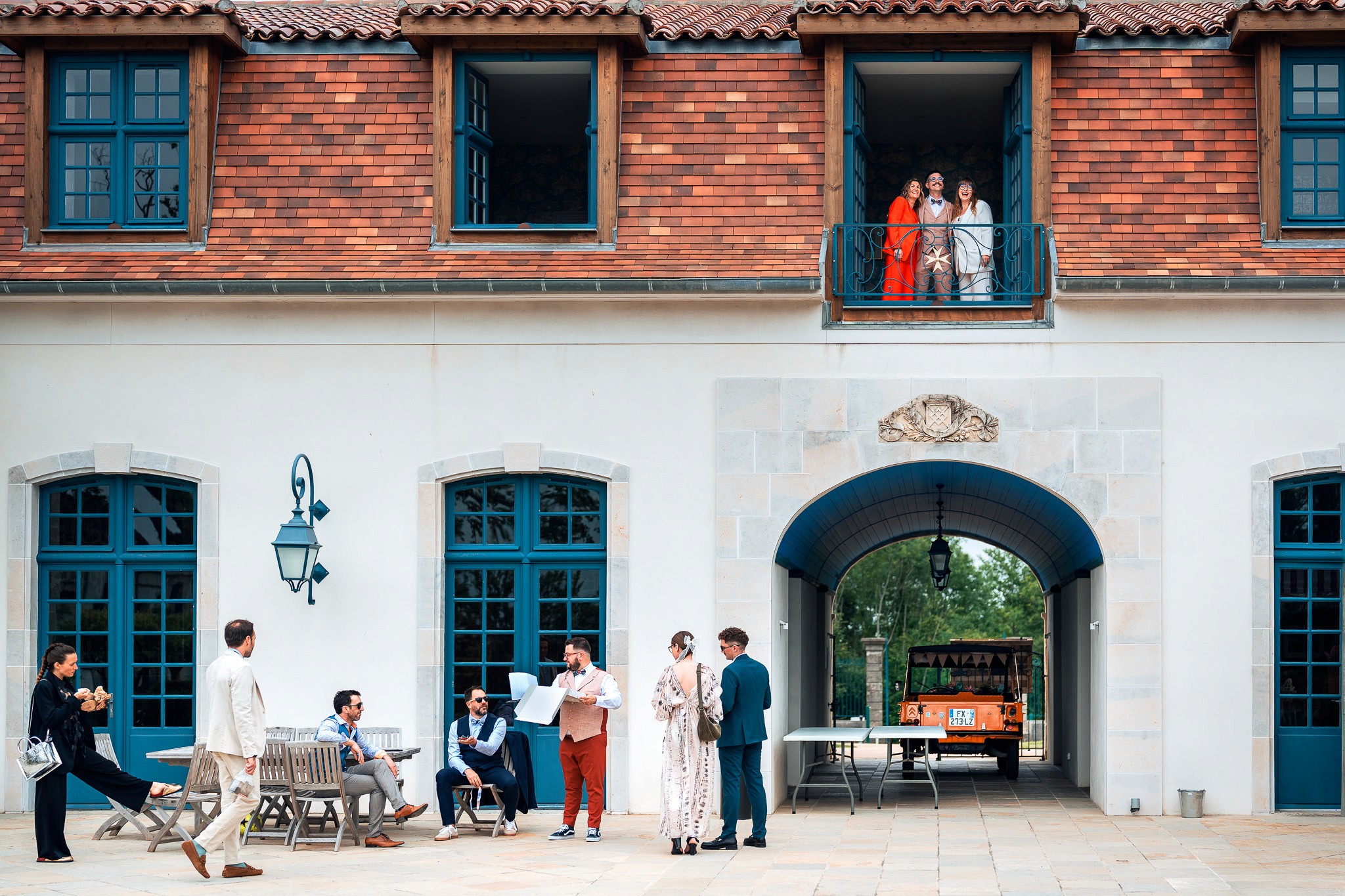 Scène de mariage au château Larraldia, invités rassemblés dans la cour pendant que des proches observent depuis le balcon, dans une atmosphère vivante et naturelle.