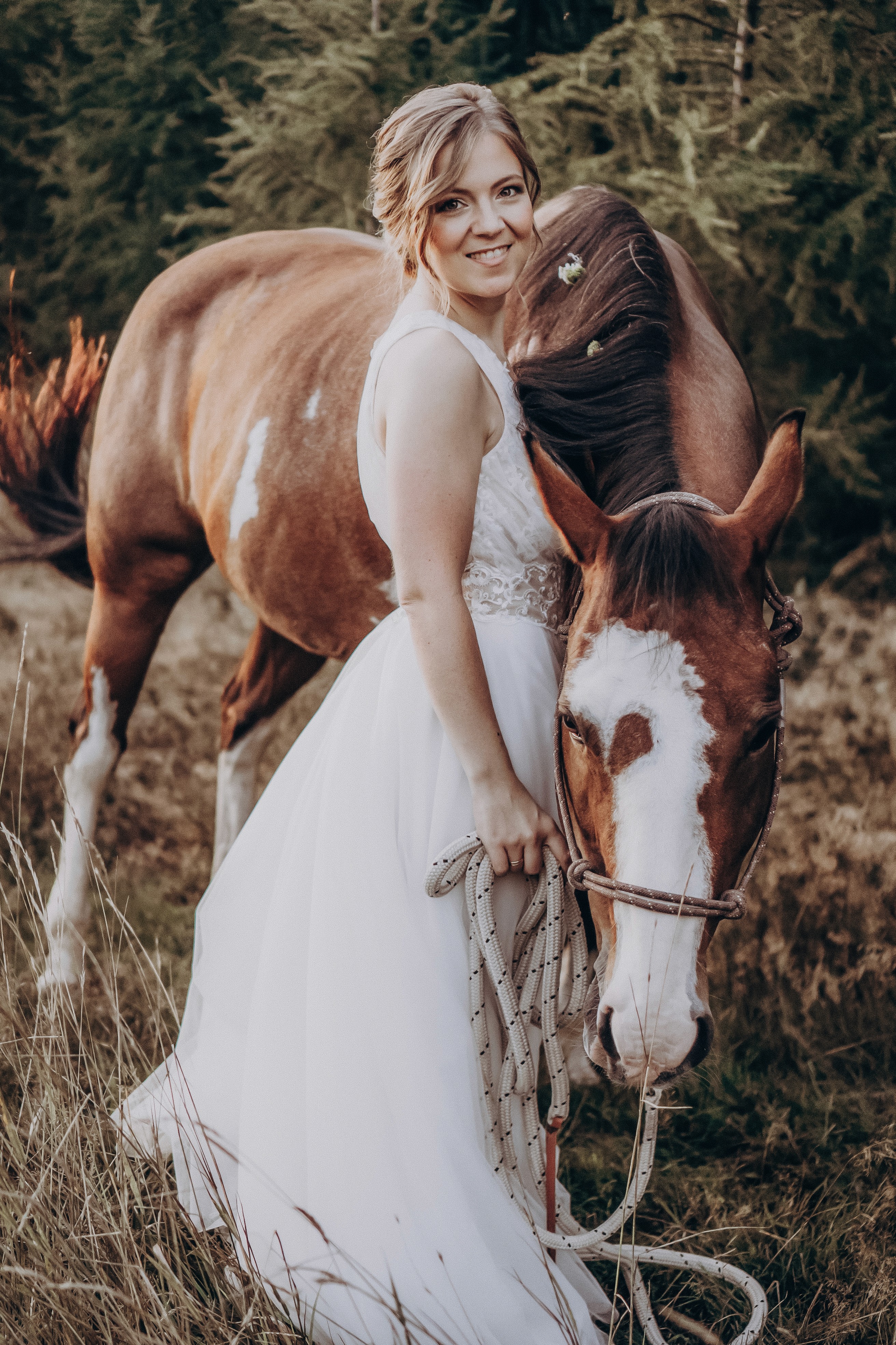 Nahaufnahme einer Braut, die liebevoll ein Pferd streichelt – Hochzeitsfotos im Freien, Bogen.