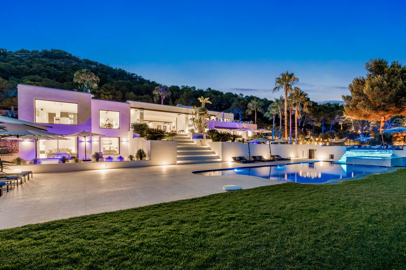 Exclusive luxury villa in Ibiza at night, showing the front facade with illuminated pool and terraces—a private VIP estate property holiday retreat for weddings and events.