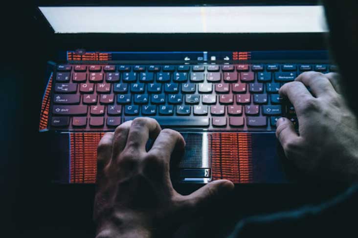 A person walks in front of large stone arches with dark doors, flanked by tall columns, in a historic building.