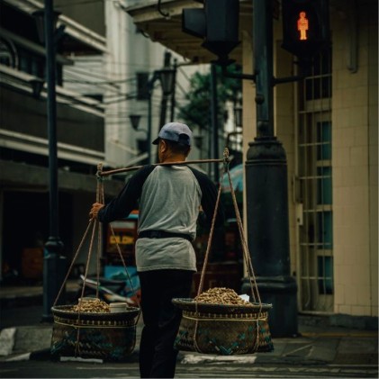 Person wearing a beige apron whisking green matcha tea in a ceramic bowl on a kitchen counter.
