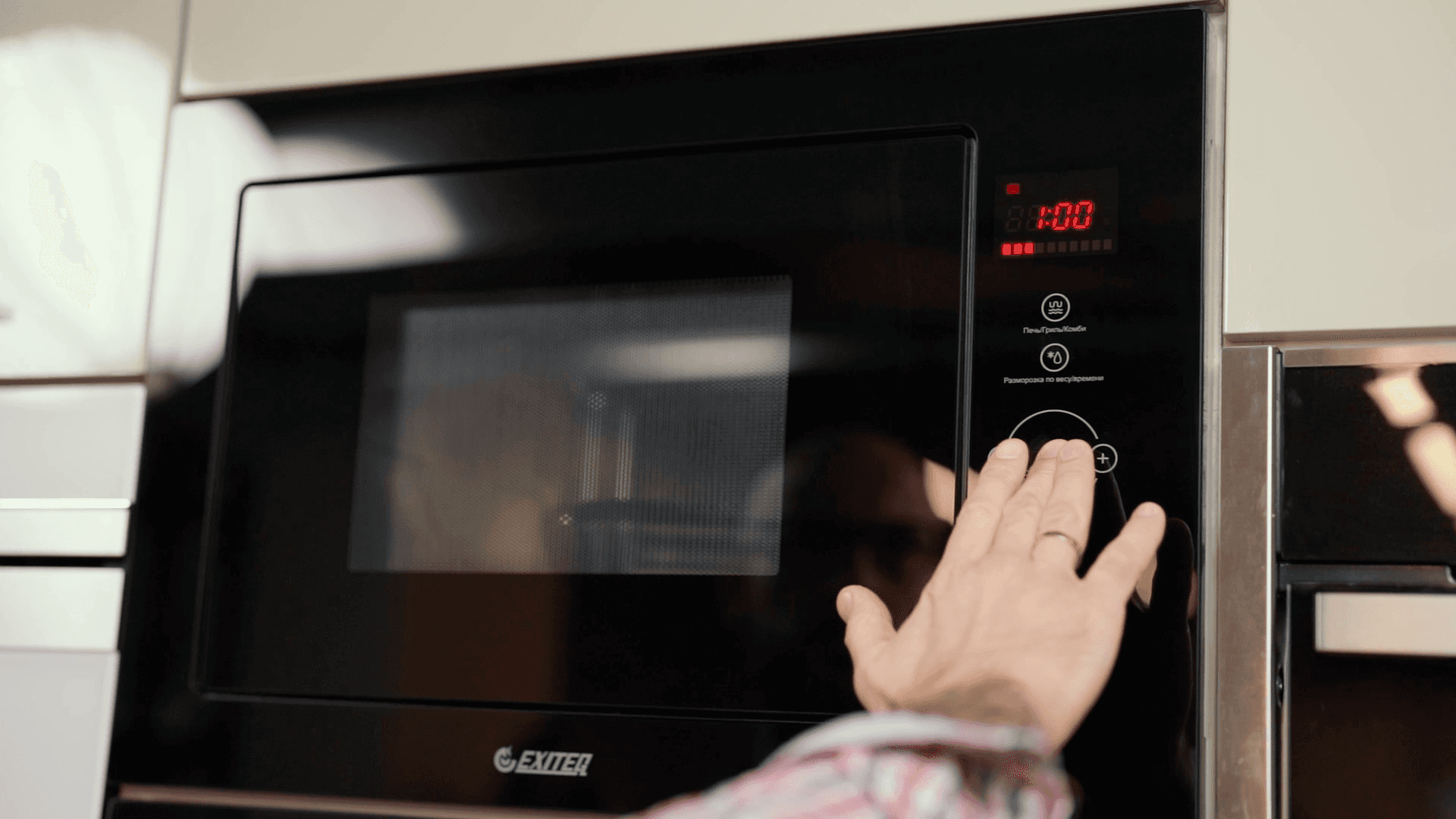A man presses buttons on a microwave oven