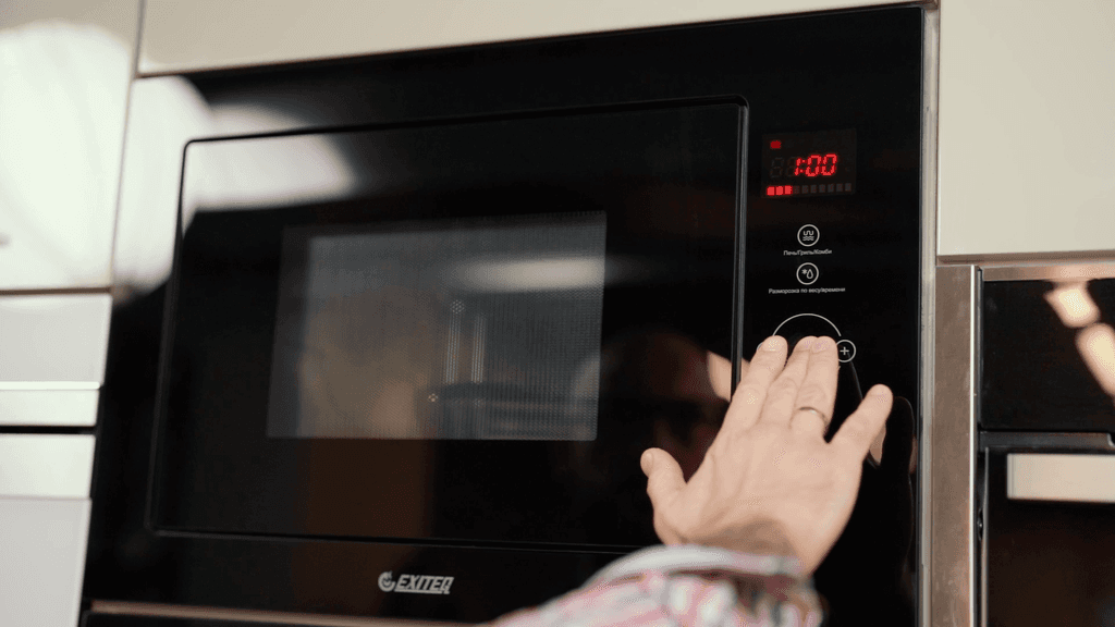 A man presses buttons on a microwave oven