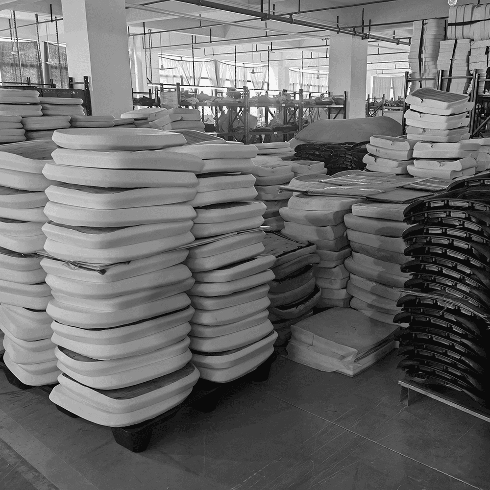 Interior of an office chair factory warehouse showing bulk inventory of seat cushions and components. This illustrates large-scale manufacturing capacity and industrial furniture production processes