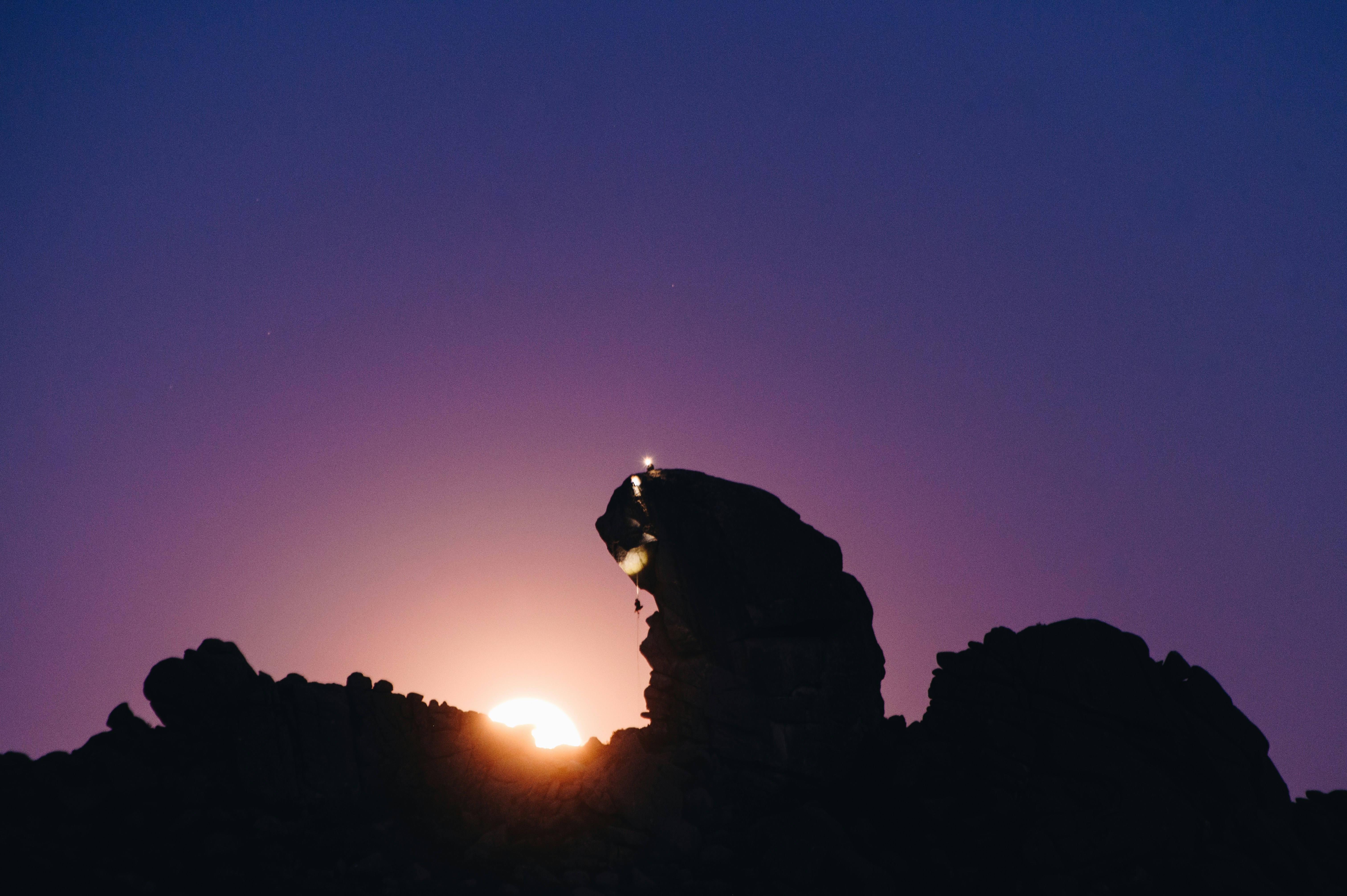 silhouette of man standing on mountain during sunset
