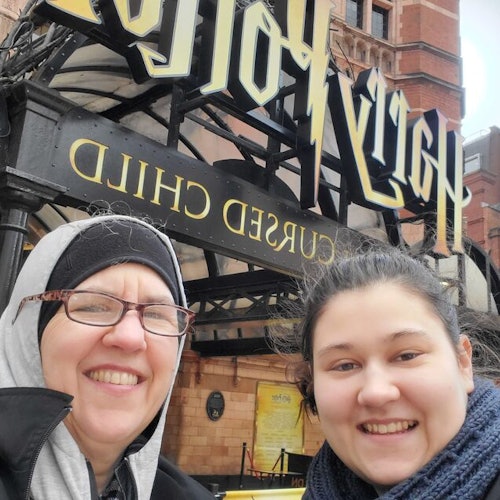 Zwei Personen lächeln vor dem Eingang des Theaters „Harry Potter und das verwunschene Kind“.