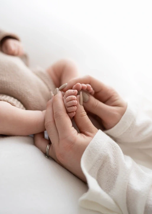 Baby feet gently held in adult hands