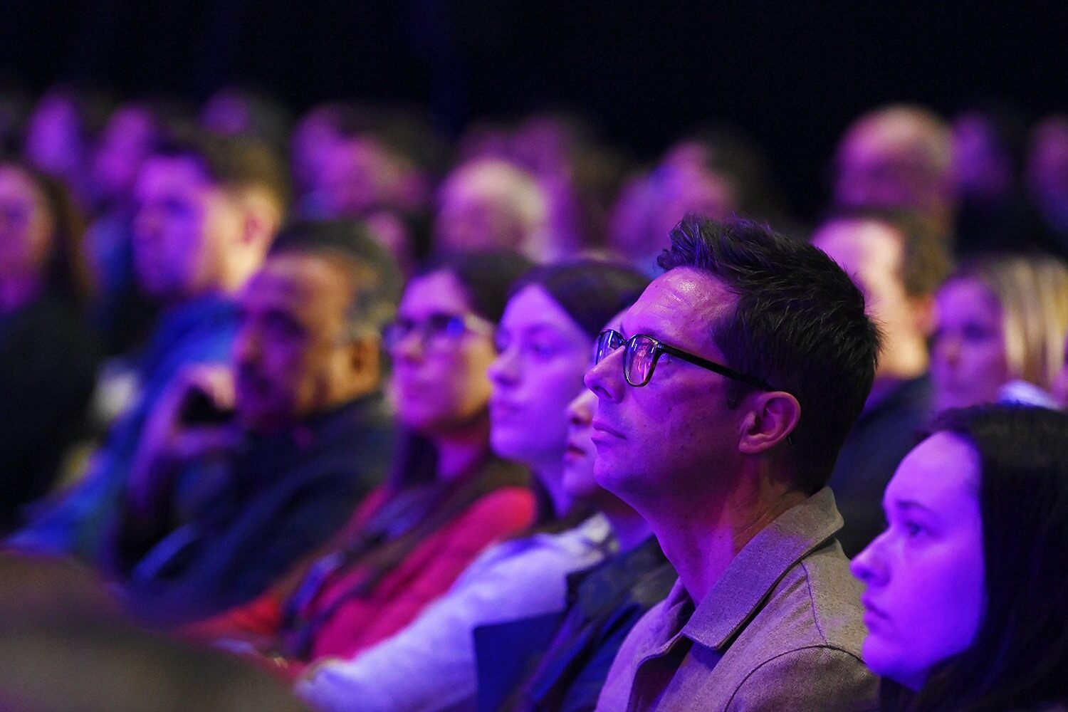 A large truck parked on a street with a bright pink carpet leading up to it, surrounded by people and trees.