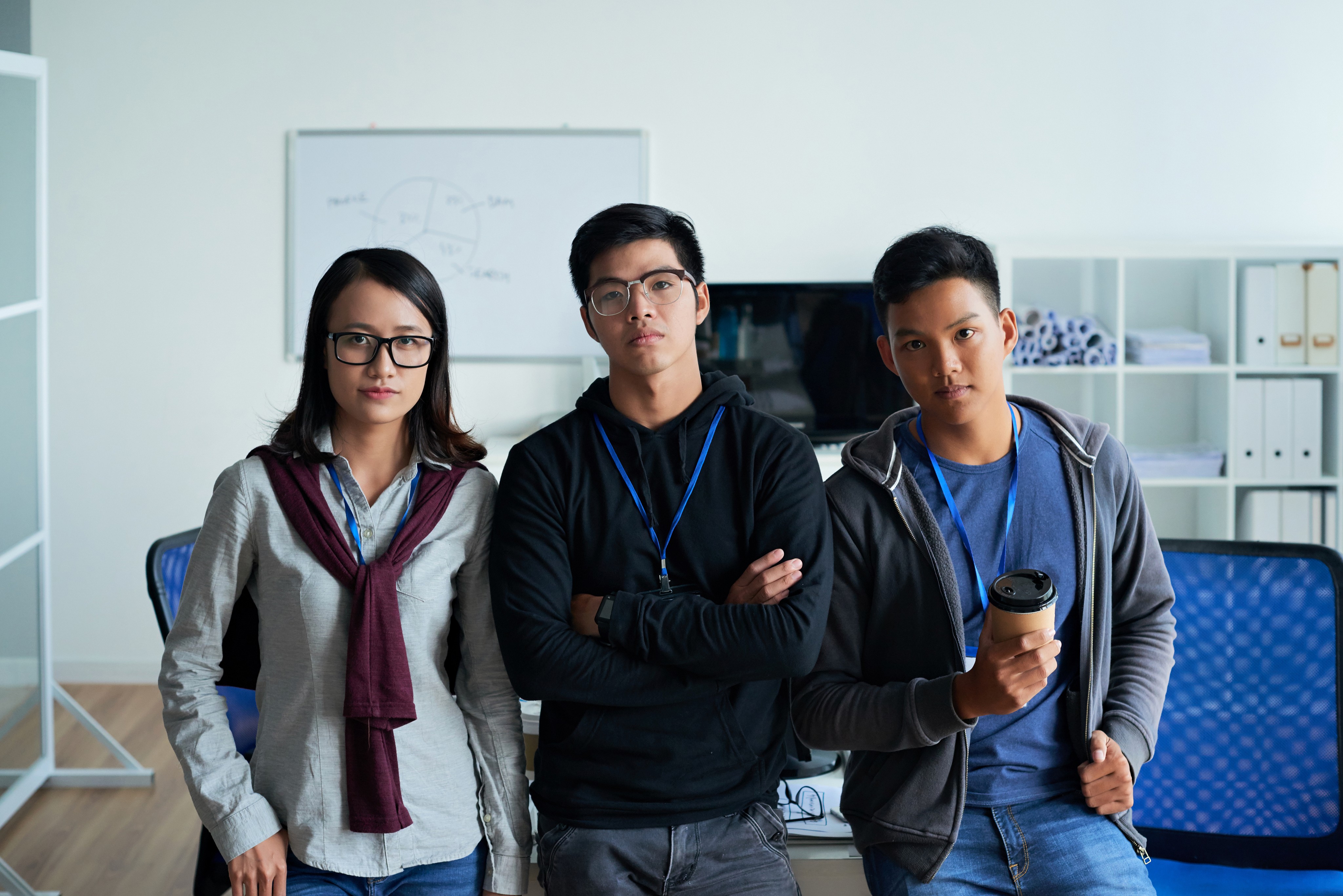 Three young professionals stand in an office, ready to enhance customer service and analytics skills for better client experiences.