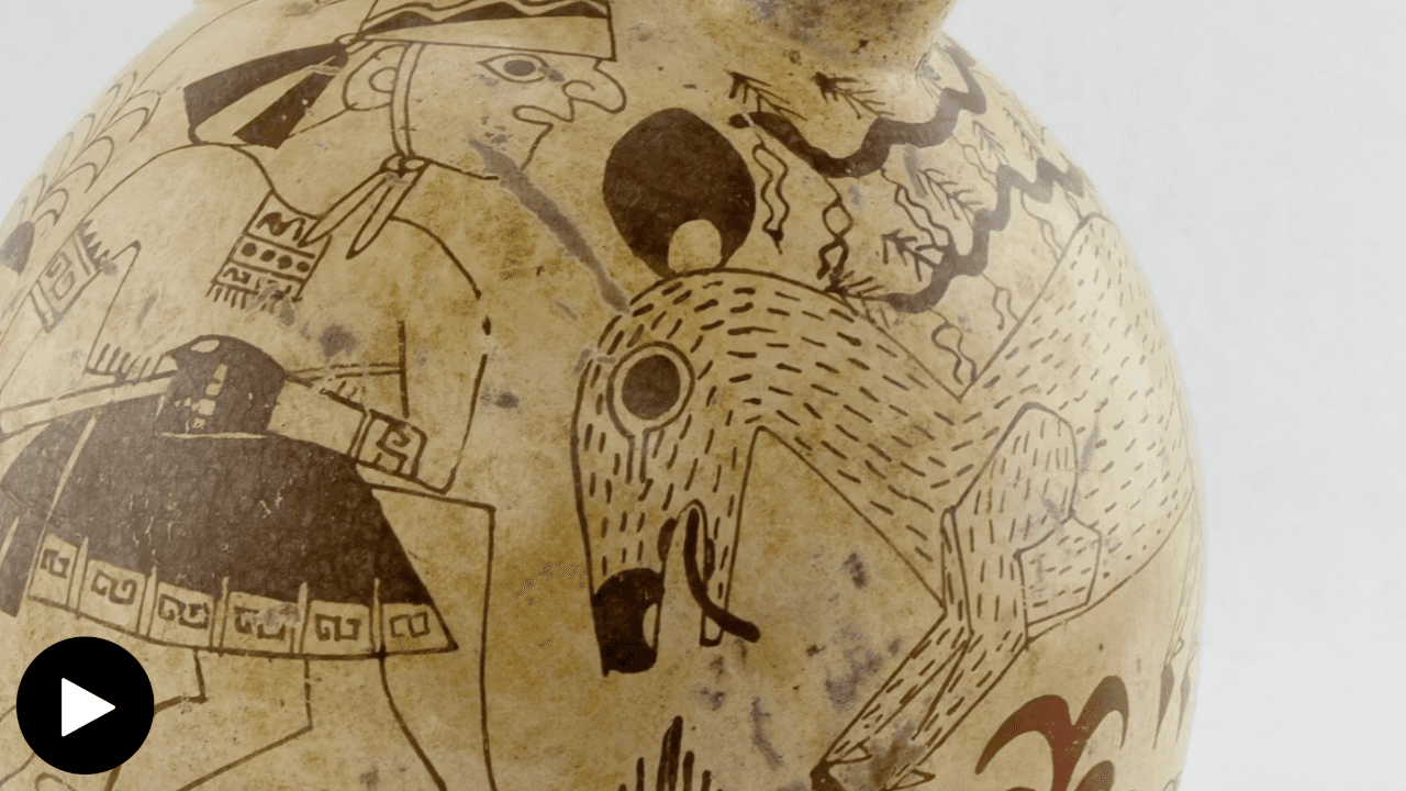 A close-up photograph of a Moche stirrup-spout vessel. It showcases a fine-line painting of a man hunting a deer.