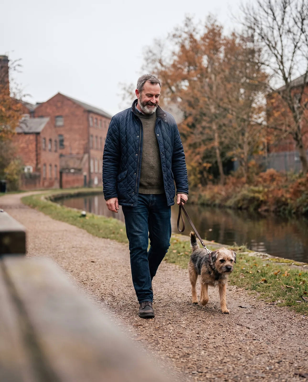 Man in his fifties walking his dog along a canal towpath