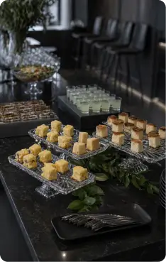 Mesa de finger foods e sobremesas finas montada para evento empresarial, com apresentação refinada em ambiente moderno e intimista.