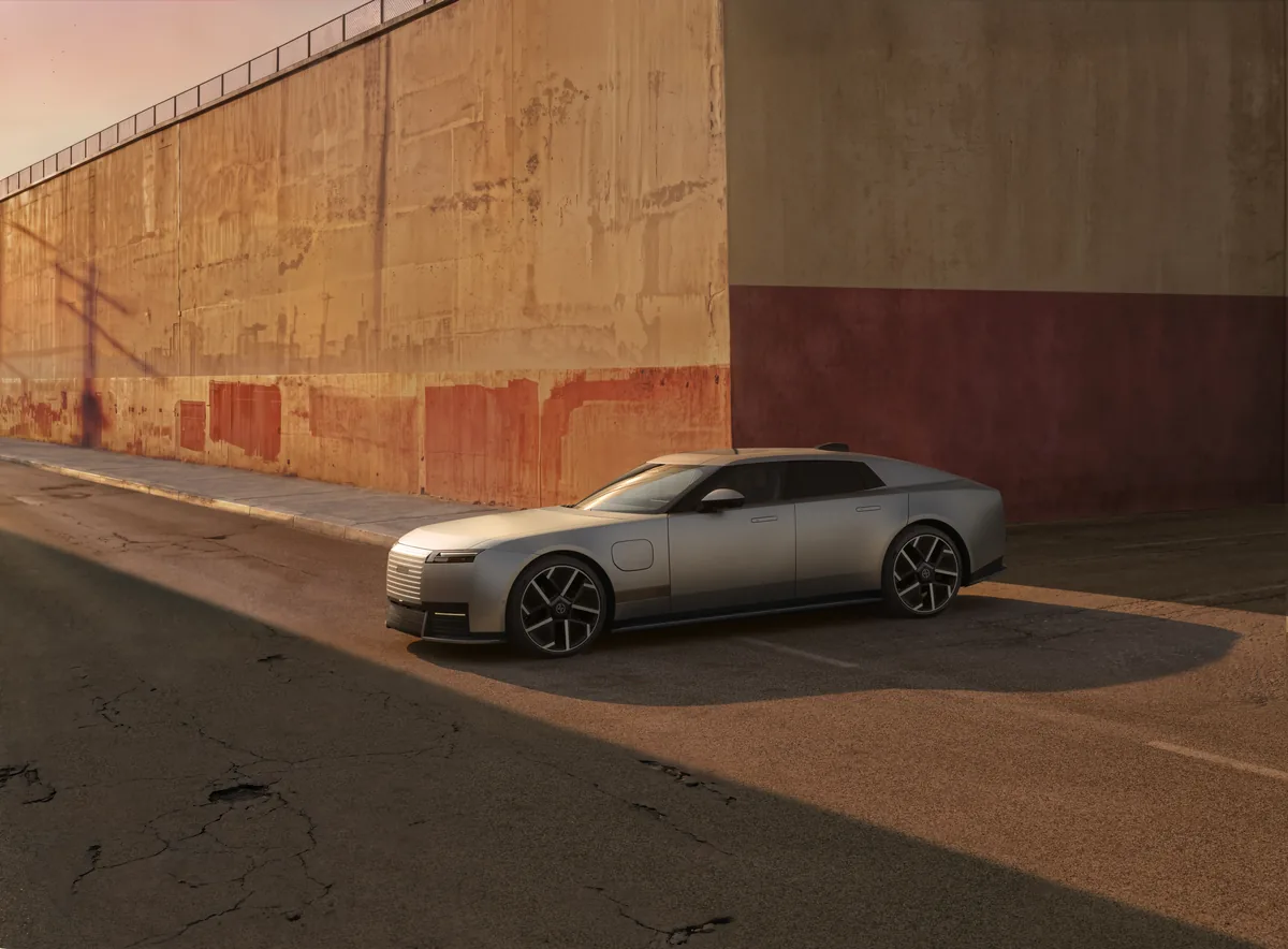 銀色 Jaguar Type 01 量產車停在暖色建築前，呈現四門車身與低車頂比例