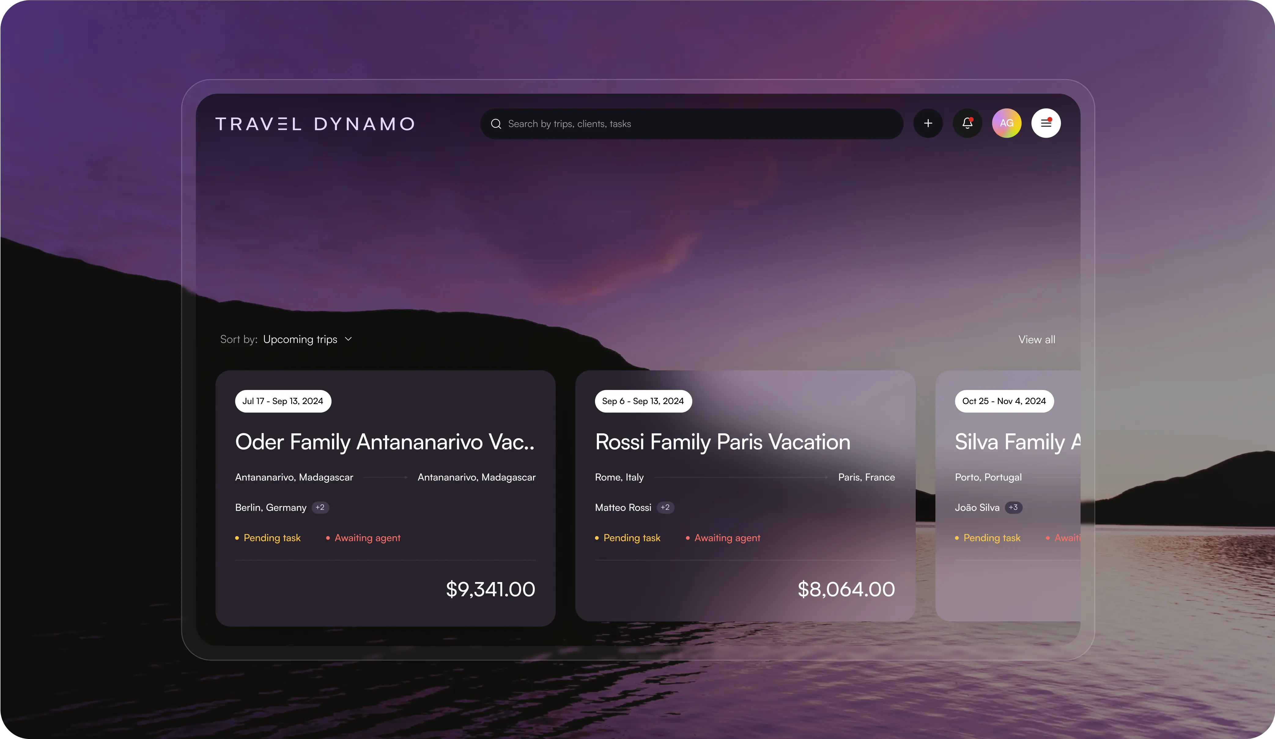 Screenshot of the 'Travel Dynamo' travel management application interface, overlaid on a serene twilight landscape. The interface displays upcoming trips for various families, including the 'Oder Family Antananarivo Vacation', 'Rossi Family Paris Vacation', and 'Silva Family Adventure'. Each trip card shows destinations, dates, the person responsible, task status such as 'Pending task' and 'Awaiting agent', and pricing information. The UI has a search bar on top with a dark purple theme, blending seamlessly with the background scene.