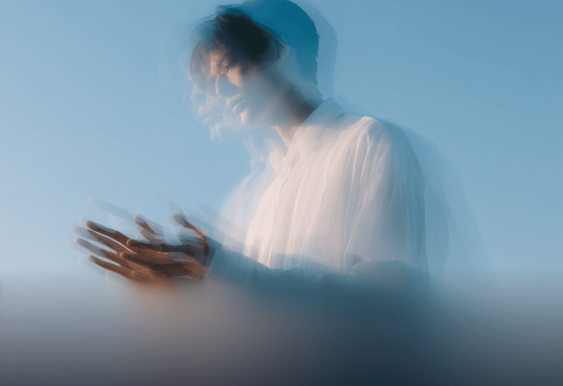 A man stands against a clear blue sky, showcasing a bright and sunny day.
