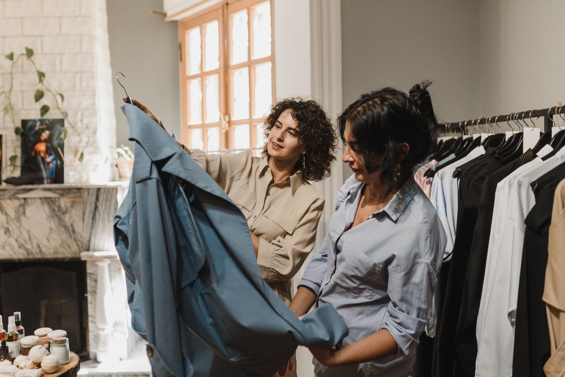 Two women reviewing clothing selections beside a garment rack