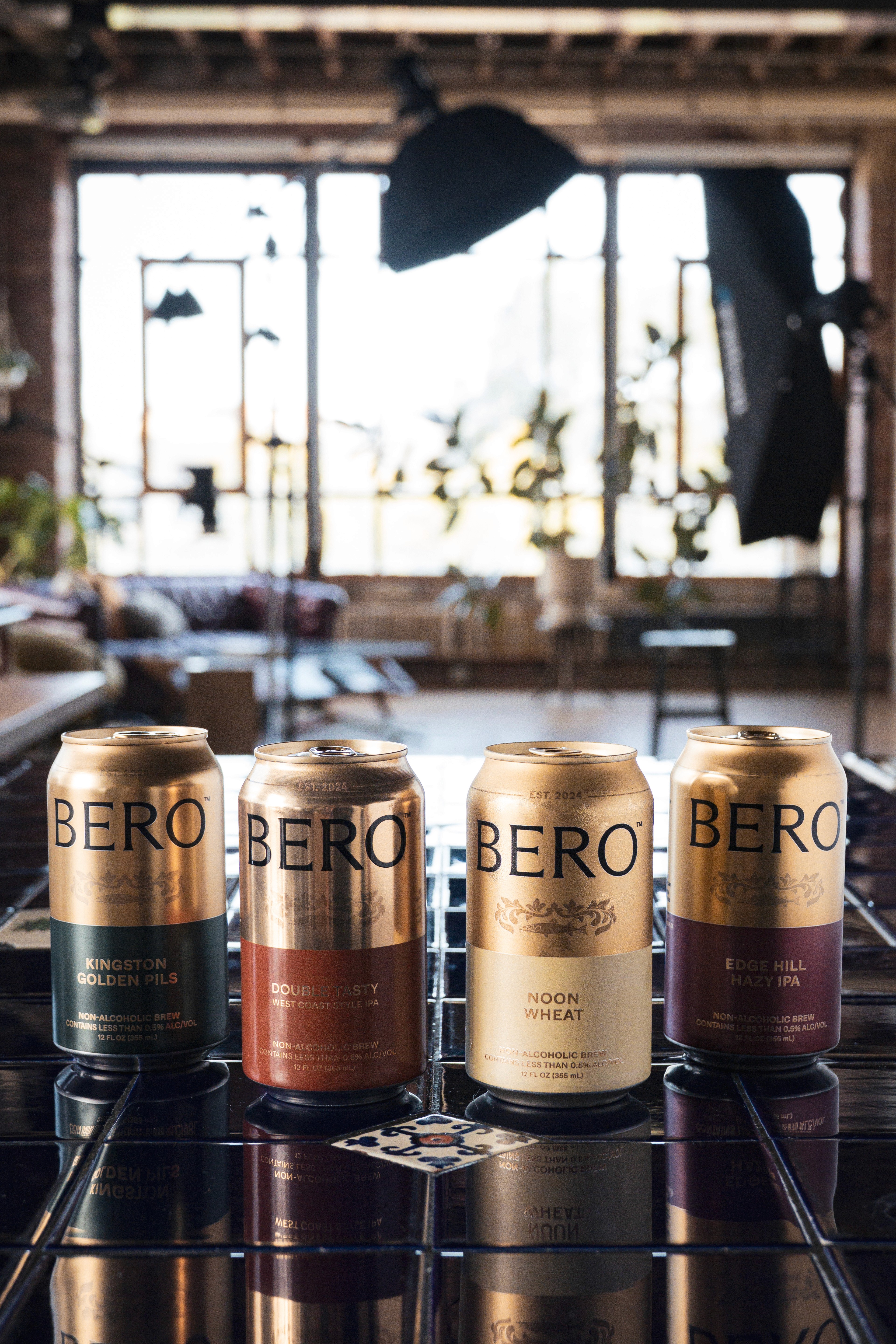 Lineup of BERO cans on a dark tabletop in a sunlit studio space.