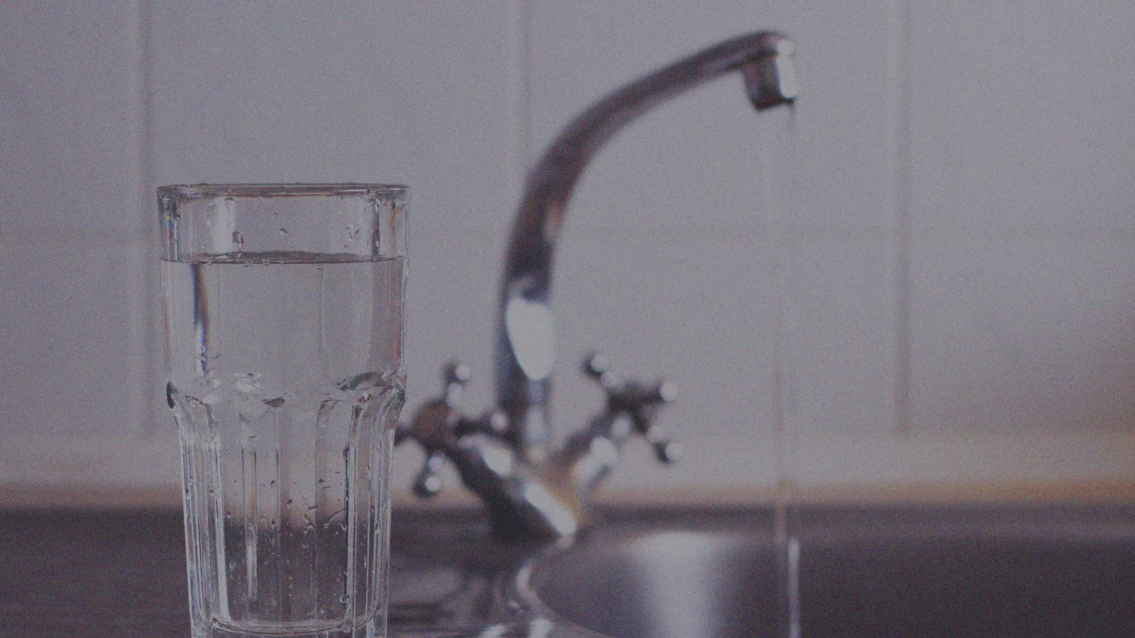 Foto de una llave de agua y un vaso en la columna de opinión "El agua que nos falta" de IdeaPaís.