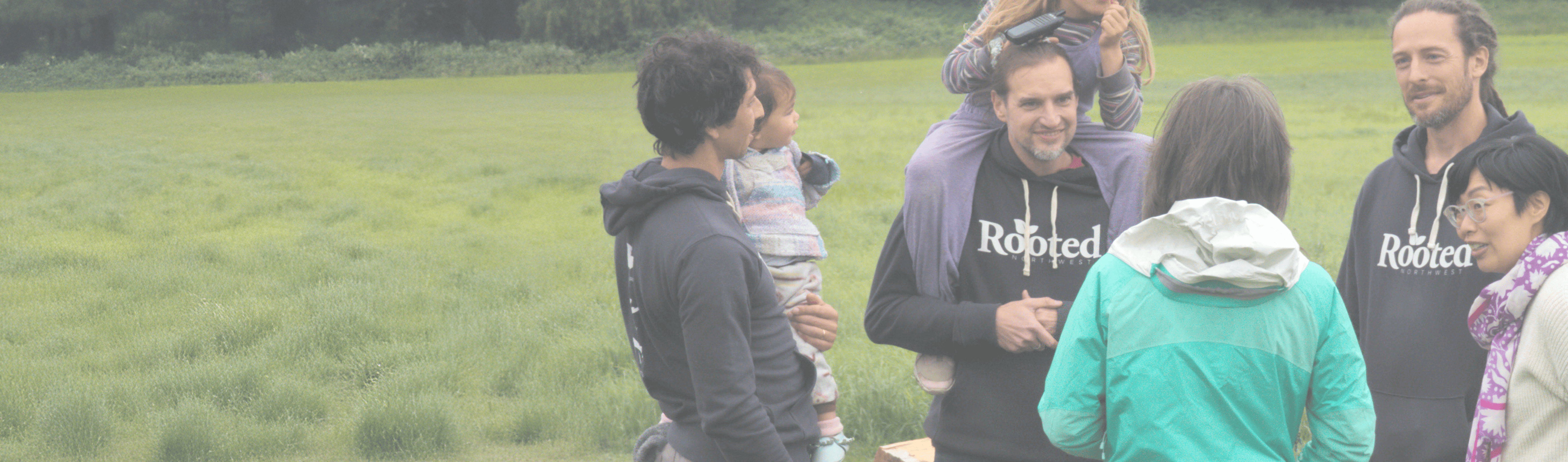 A group of people standing together in a field, representing community support for local agriculture.