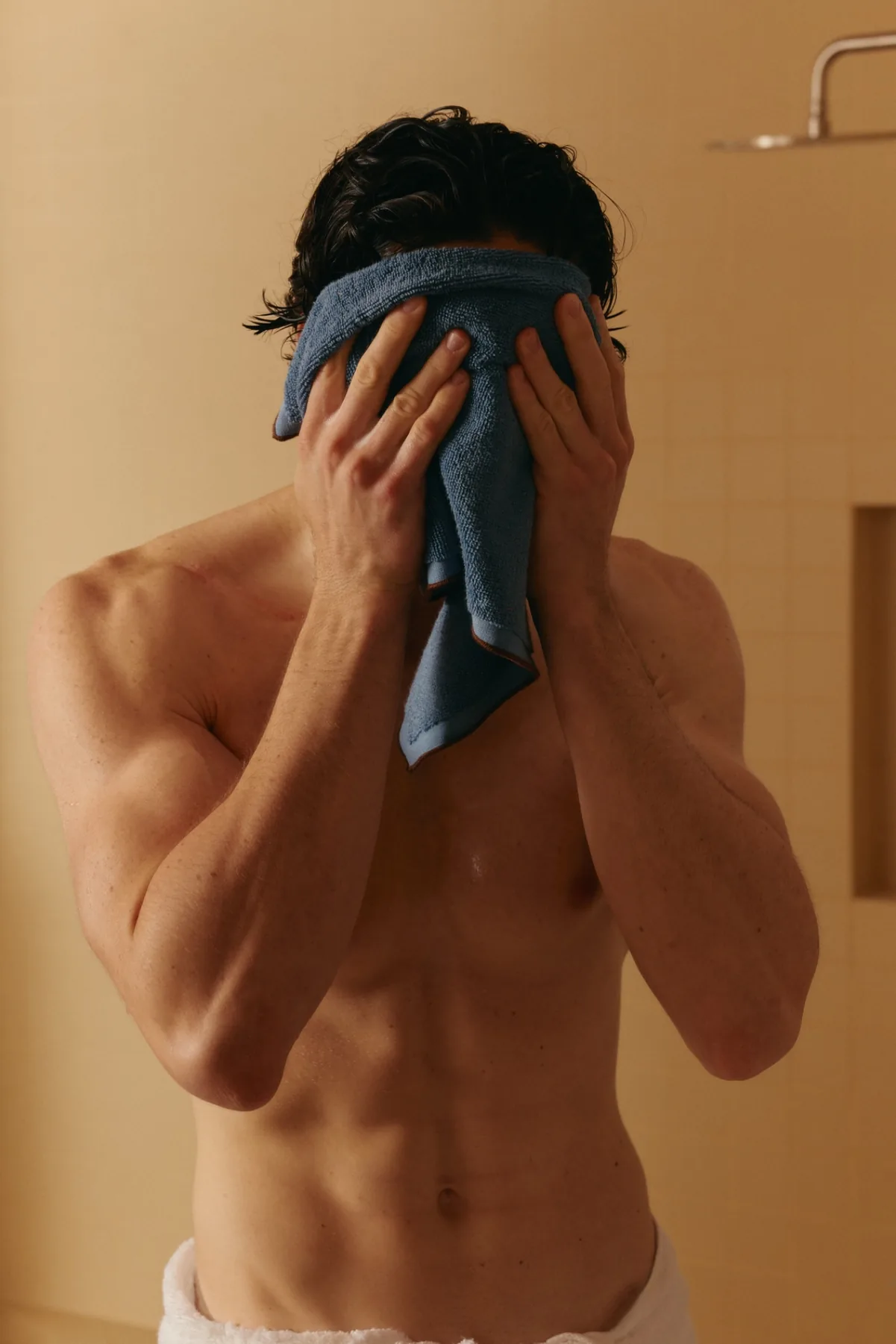 A man drying his face with a towel after a shower