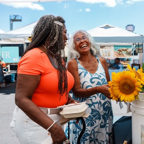 A vibrant and adventurous African American senior woman cheerfully talks with her home aid.