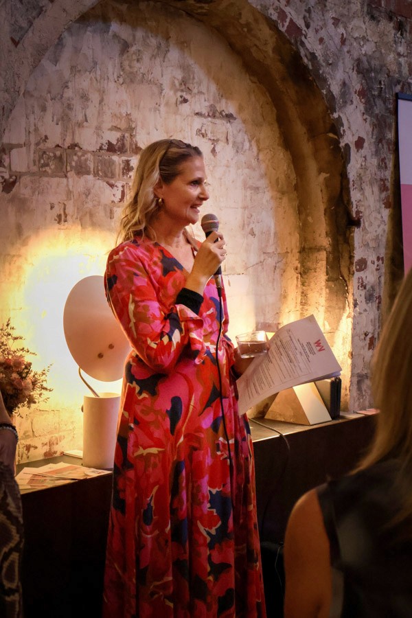 woman faces crowd with a microphone and speech in hand