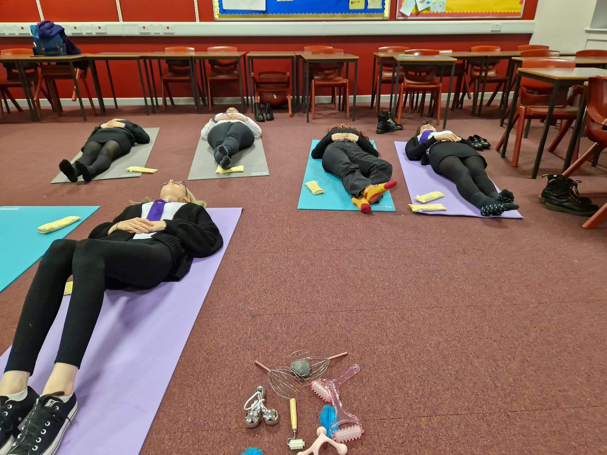 A group of young people lying on their backs with their hands on their stomach