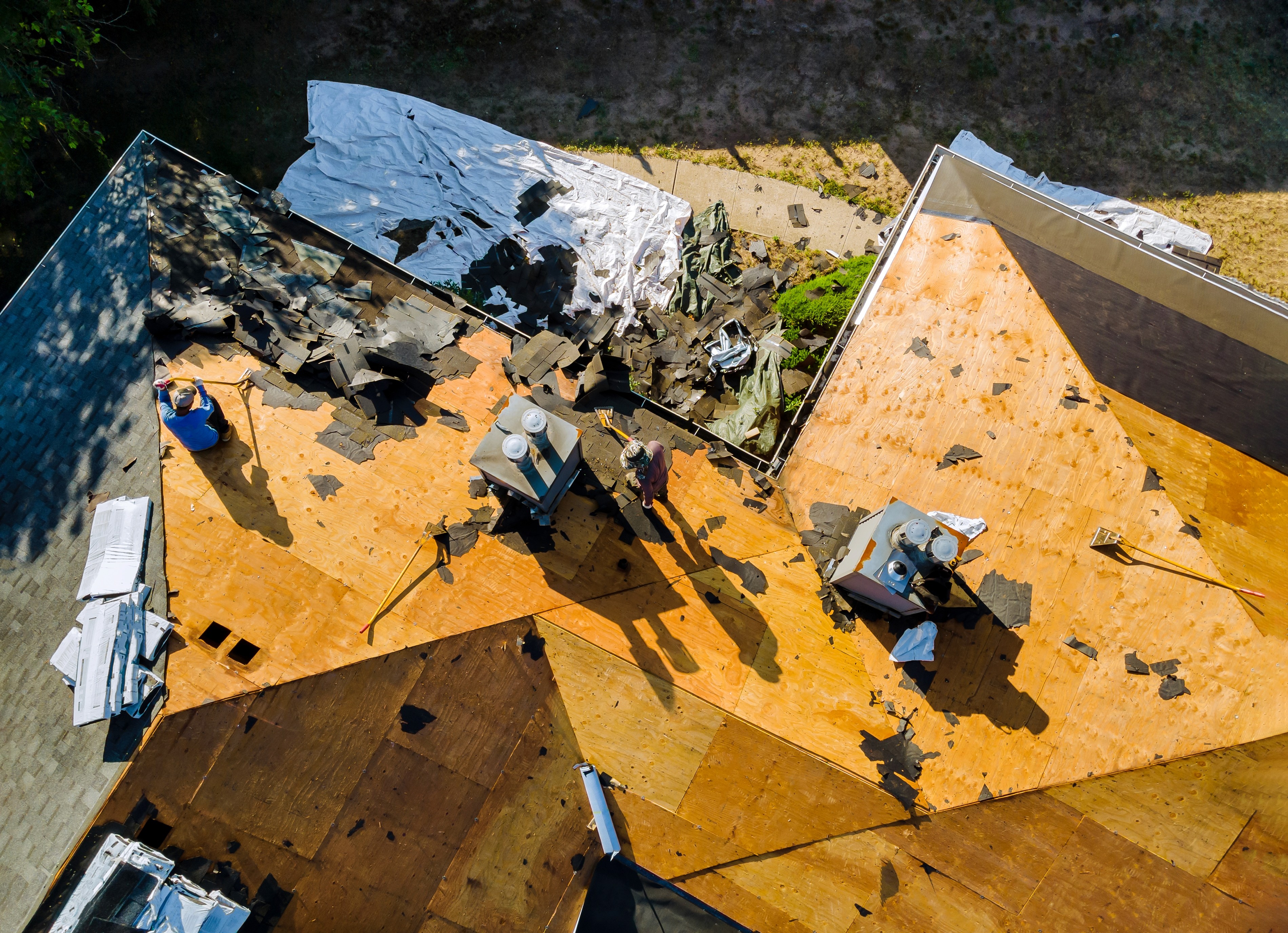 Aerial view of roof repair after tornado damage in St. Louis, showing removed shingles and exposed plywood decking during restoration work