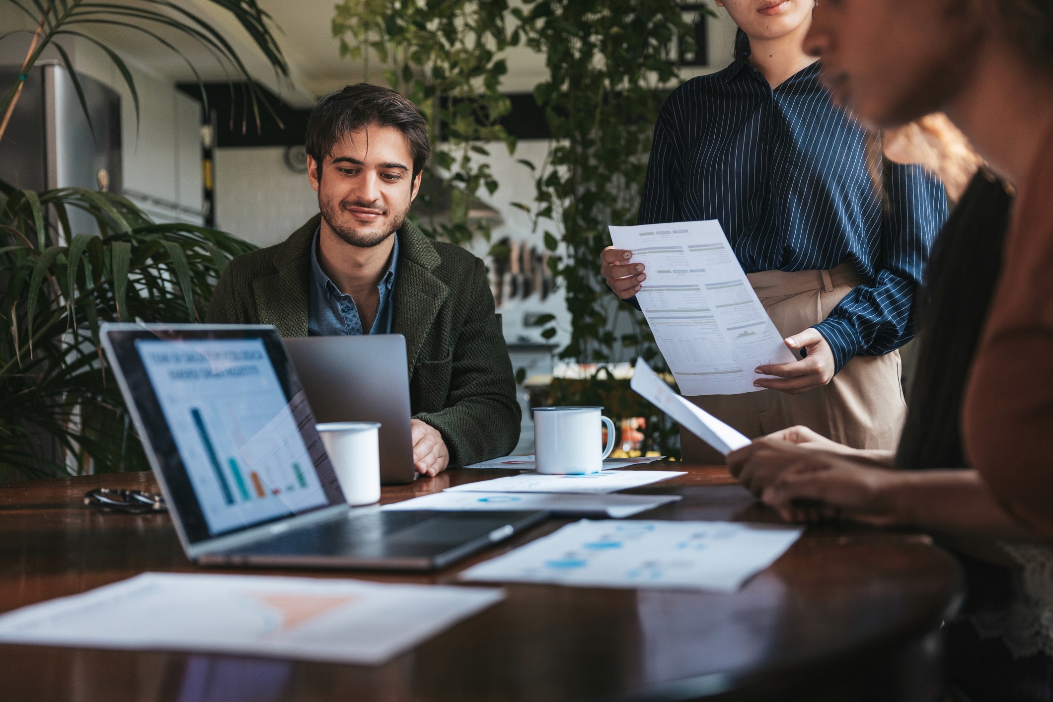 A team in a light and airy office looks at a bar chart on a laptop together.